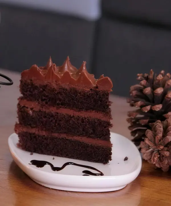 Una porción de torta de chocolate de tres capas en un plato blanco
